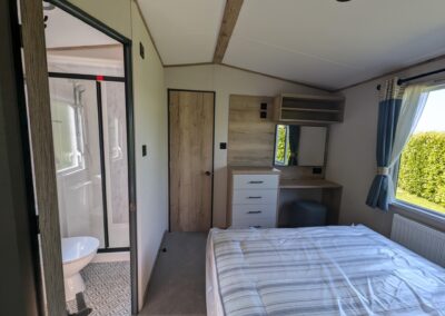 Master bedroom with vanity area and stool, looking into the en suite shower room